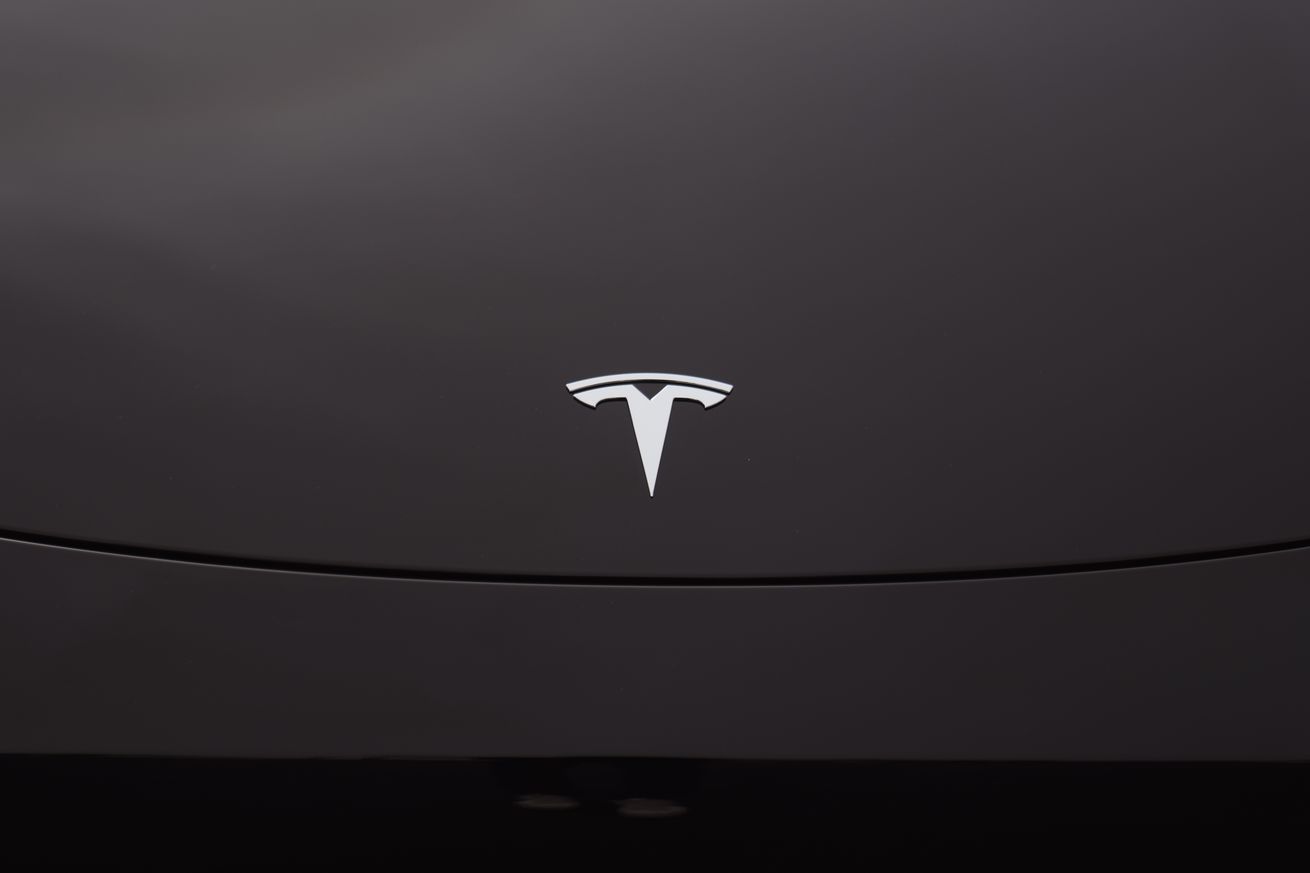 Μια εικόνα που δείχνει το λογότυπο της Tesla σε ένα μαύρο όχημα