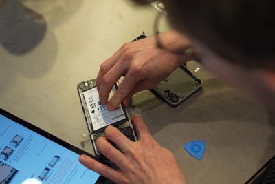Ένα άτομο που σηκώνει την μπαταρία του Nokia G22 από το τηλέφωνο.