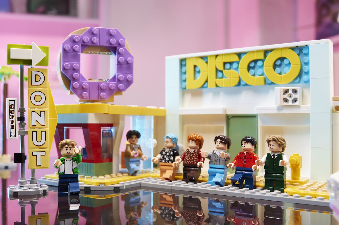 Αγαλμάτια Lego BTS τοποθετημένα έξω από ένα κατάστημα ντίσκο και ντόνατ Lego.