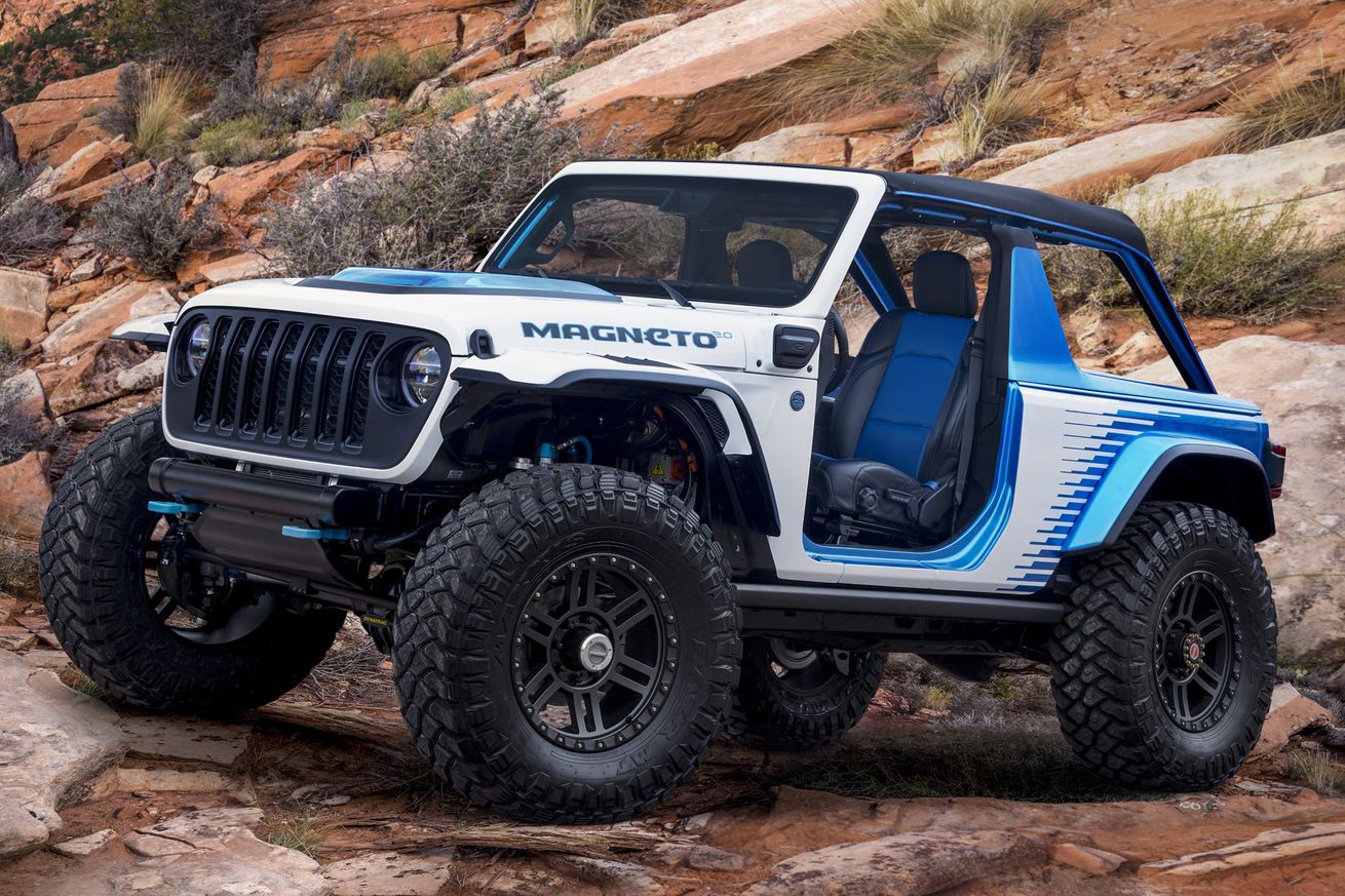 Φωτογραφία ενός μπλε και λευκού Jeep Wrangler που οδηγεί σε βράχους.