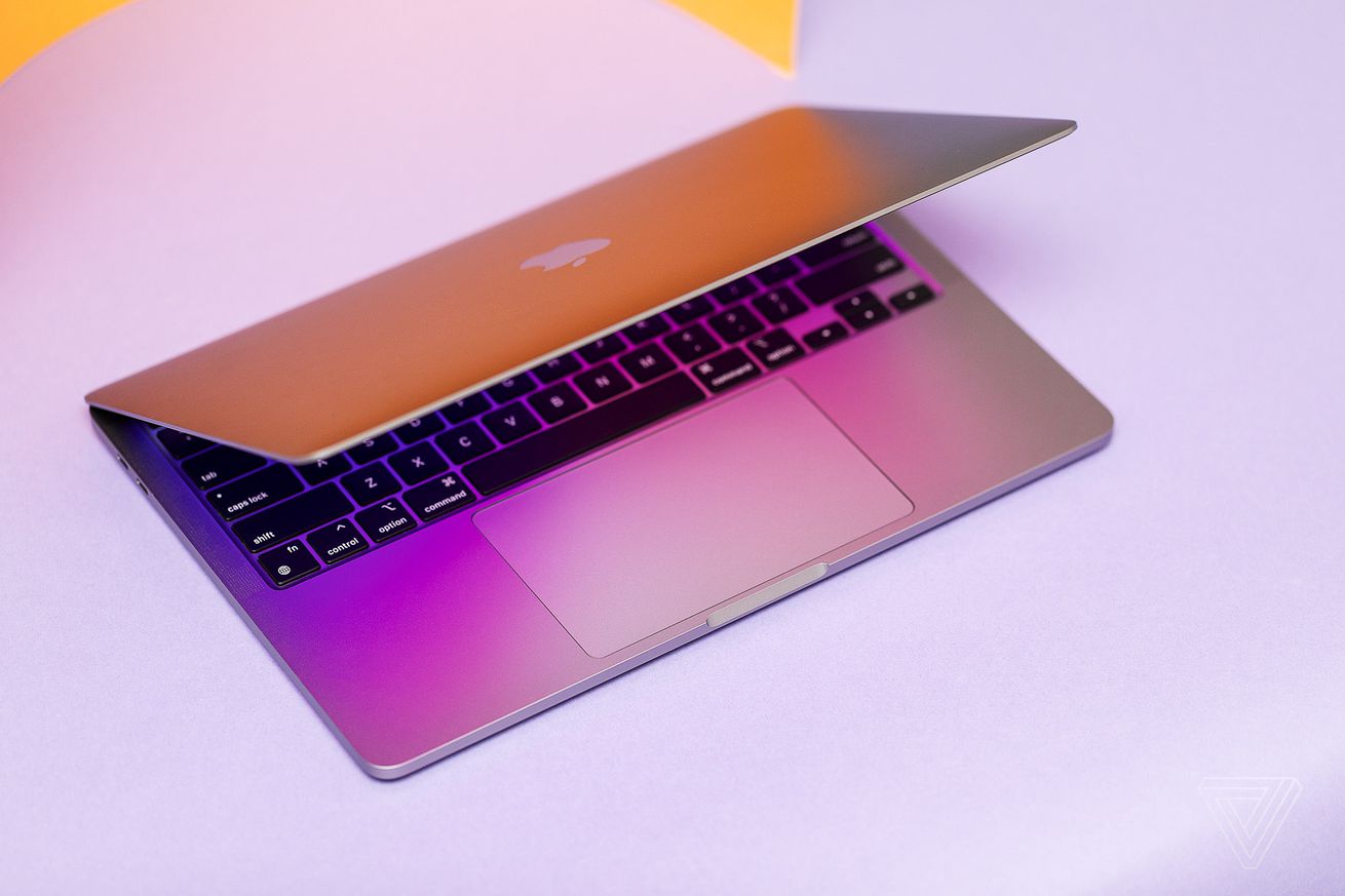 Το MacBook Pro 13 2022 μισάνοιχτο φαίνεται από ψηλά σε φόντο λεβάντας.