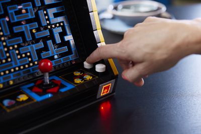 Ένα άτομο πατάει ένα κουμπί στο ντουλάπι arcade, με αποτέλεσμα να ανάβει η θυρίδα του.