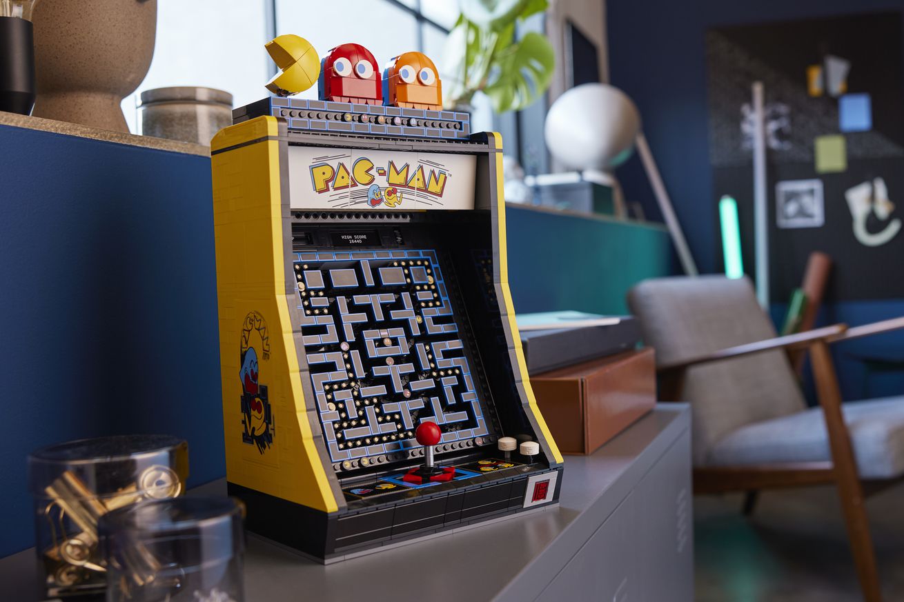 Ένα ντουλάπι arcade lego pac-man σε ένα πολυσύχναστο δωμάτιο.